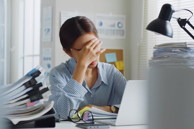 Woman at her desk covering her face due to stress