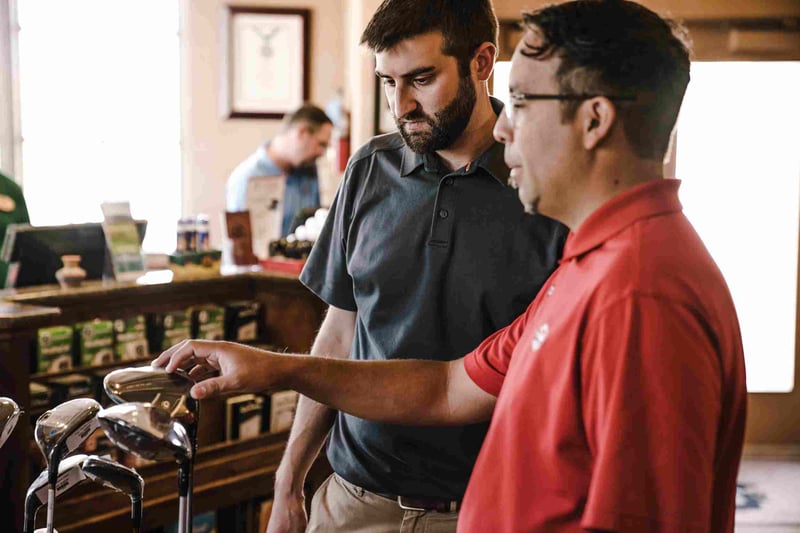 Two men talking beside golf clubs