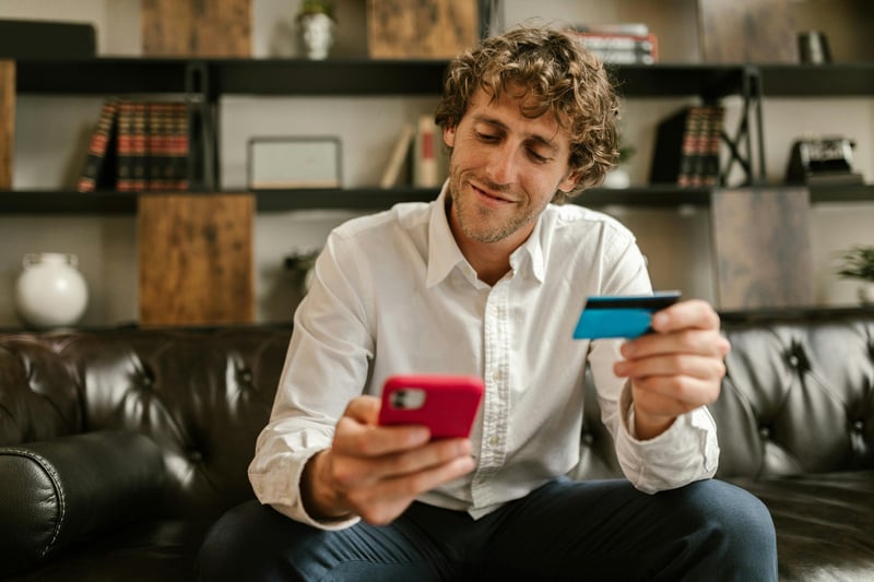 man sitting on a sofa while using his virtual payment cards
